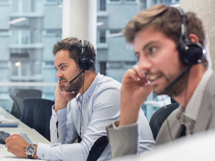 Two men answering calls with headsets